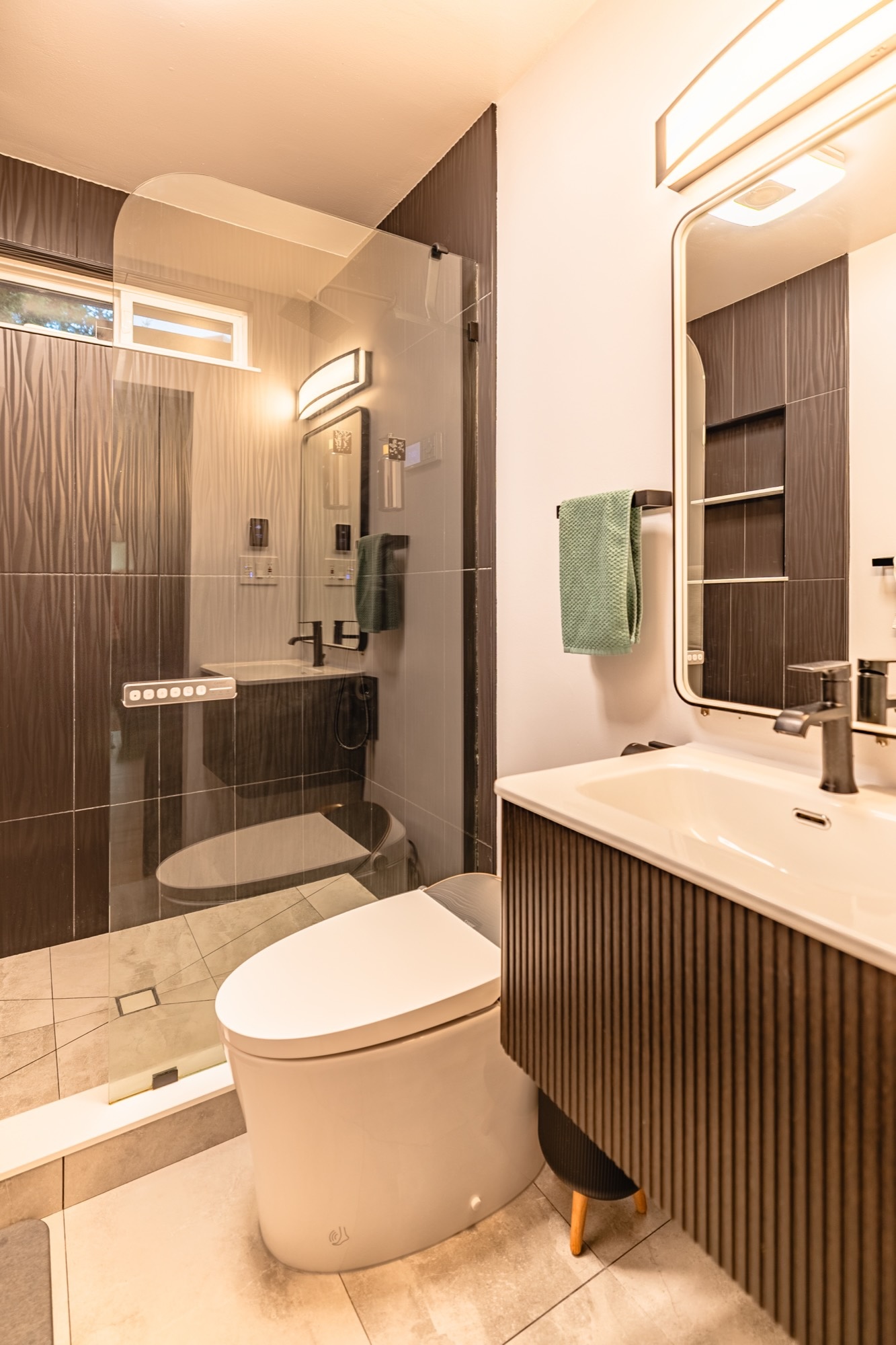Bathroom with a glass-walled walk-in shower, dark textured tile, a bidet toilet and a ribbed wood vanity.