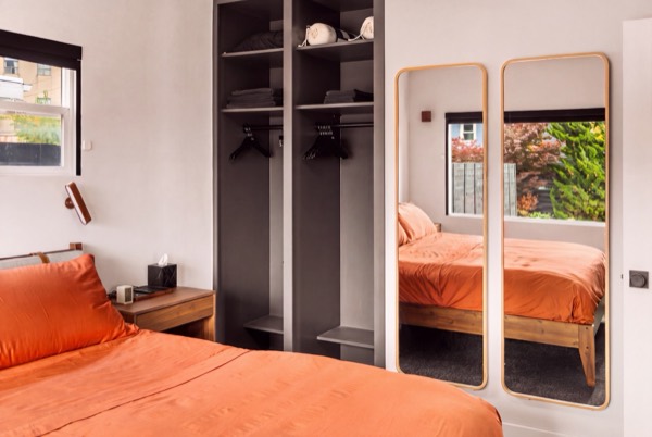 Open closet shelves with hangers beside two tall wood-framed mirrors, at the foot of the king bed