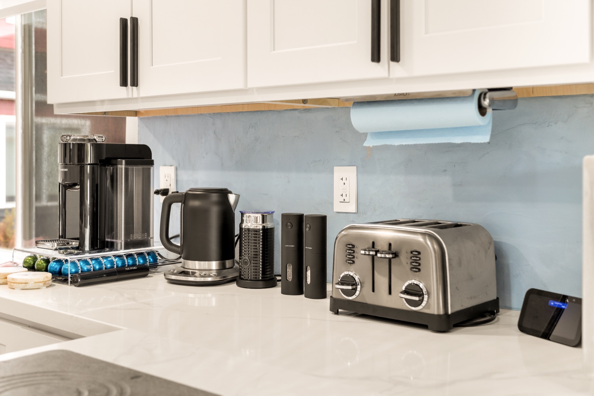 Coffee corner on the kitchen counter: a capsule coffee machine with a rack of capsules, a kettle, a grinder and a toaster