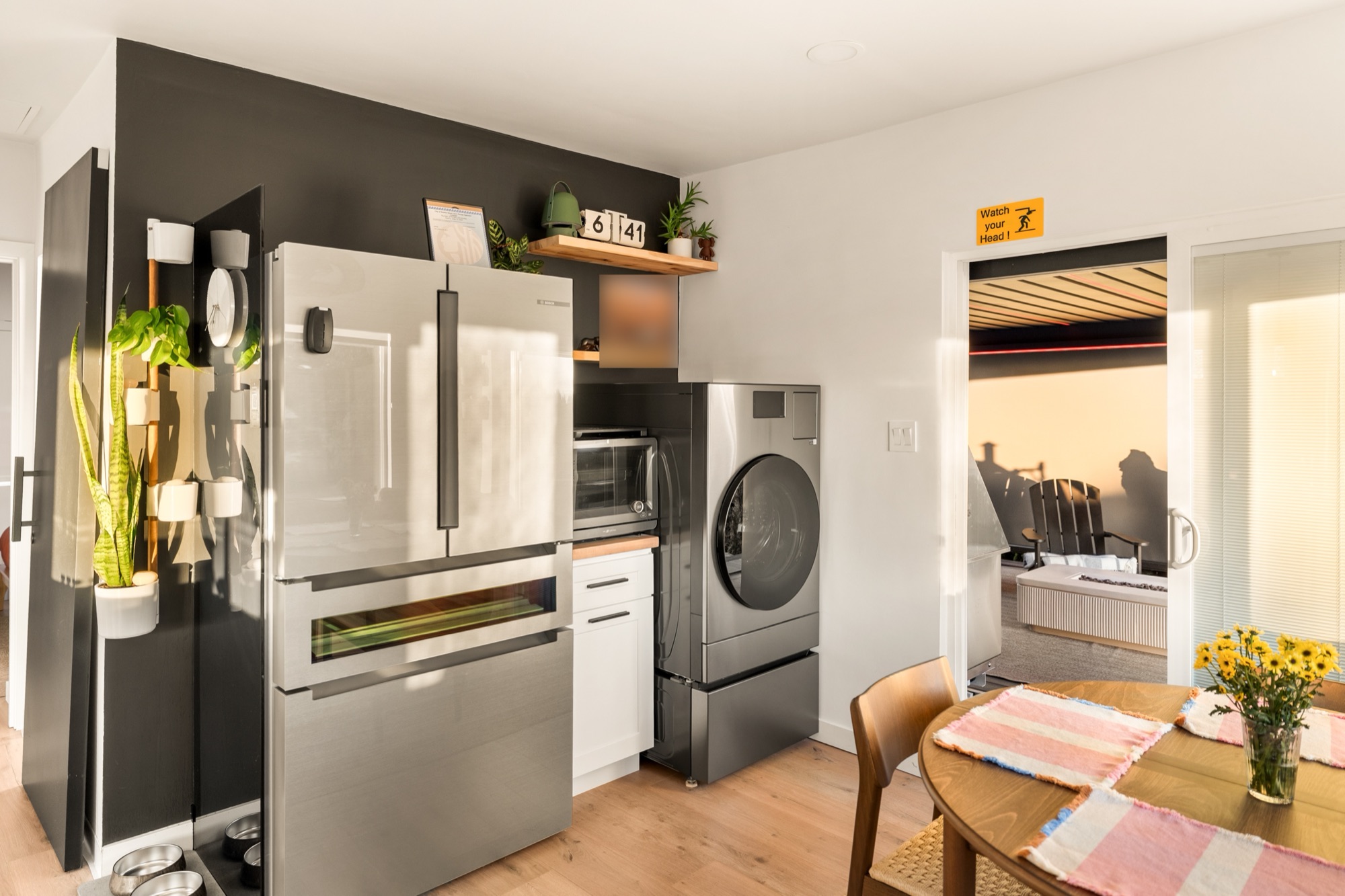 A stainless French-door fridge beside an all-in-one washer-dryer, off the kitchen
