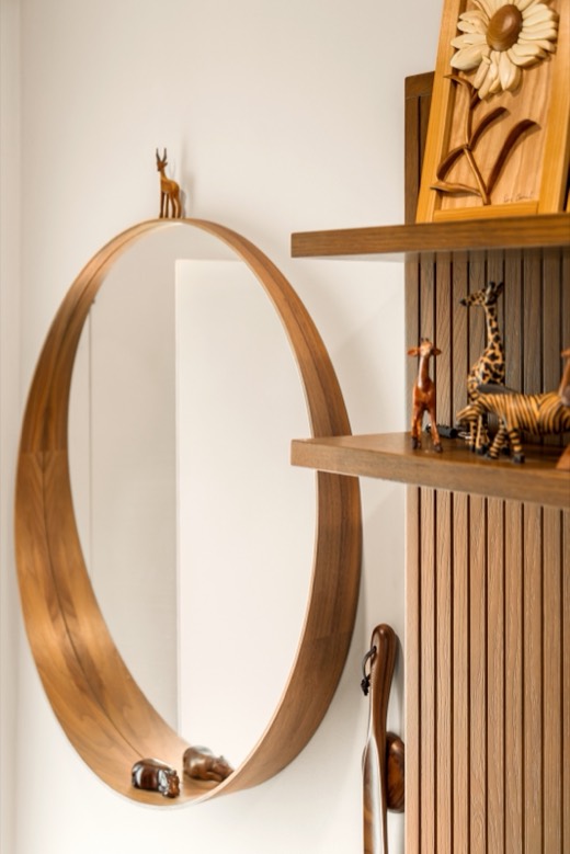 A round wood-framed mirror beside wood slats and a shelf of small carved wooden animals